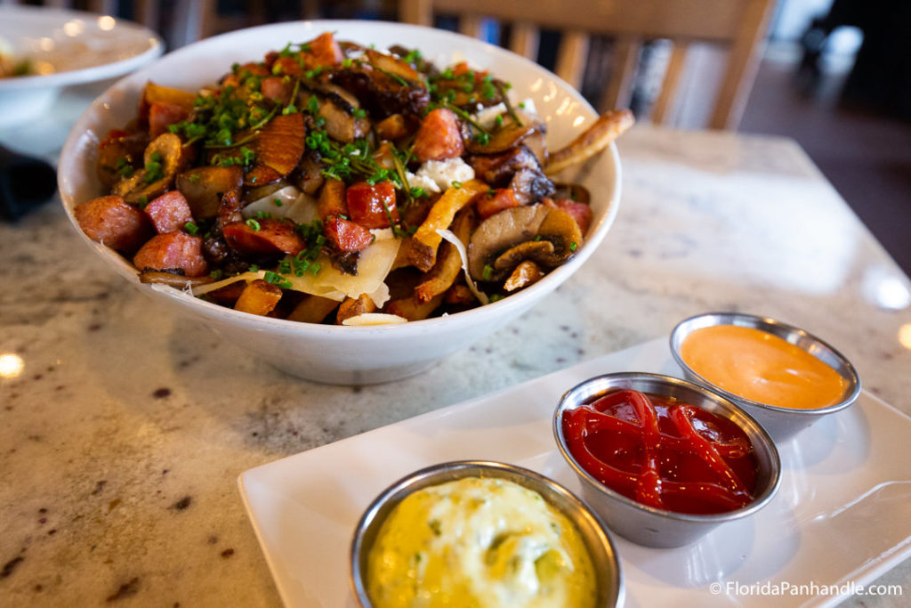 loaded fries with mushrooms and other fresh veggies on top with a side of ketchup on the side at George Bistro and Bar