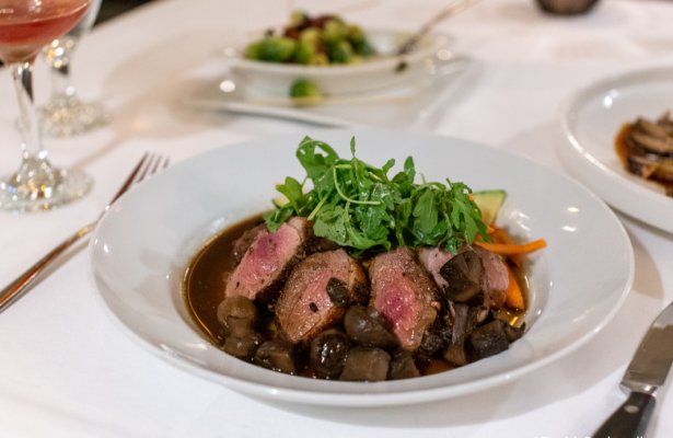 a plate of medium rare steak with mushrooms on the side and a greens on top at Global Grill 