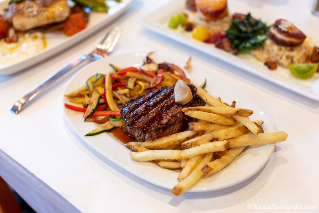 a plate of steak with a side of fries and slices on cooked zucchini at Jackson's Steakhouse