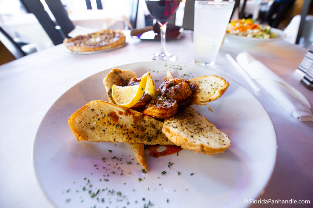 A plate of cajun shrimp on a bed of sliced bread and a lemon slice on top at Lillo's Tuscan Grille 