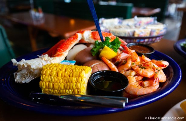a blue plate with shrimp, corn and crab legs