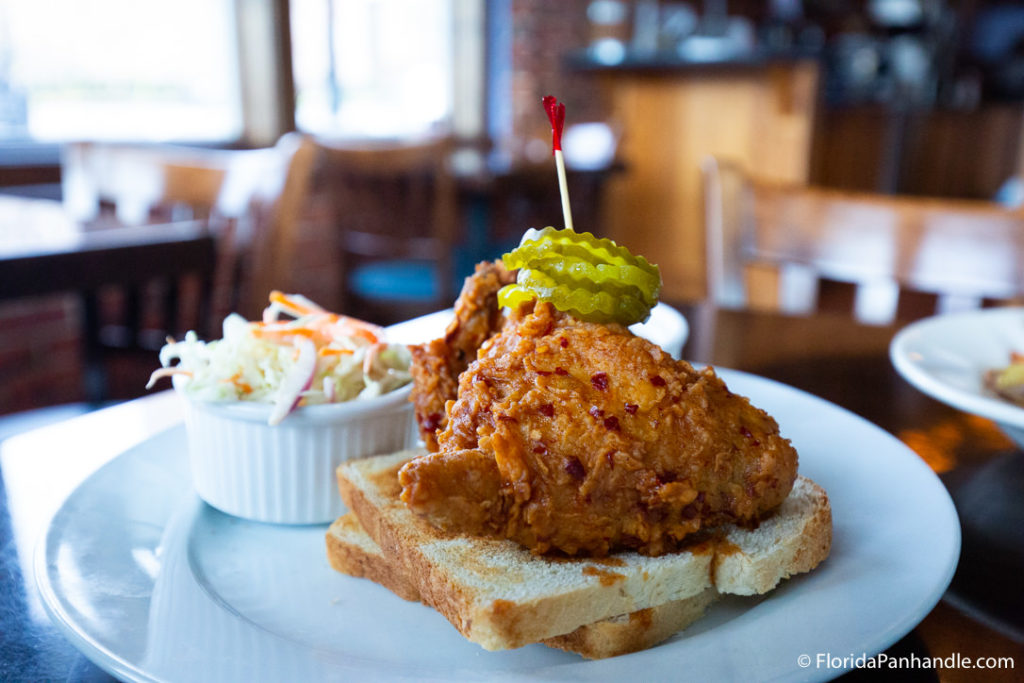 a plate of fried chicken on top of two slices of toast with pickles in top with a side of coleslaw at Polonza Bistro