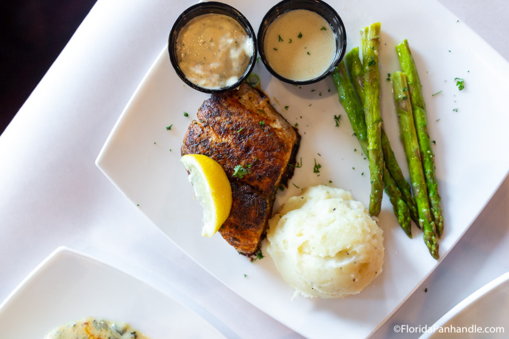 above view of fish with lemon wedge on it next to mashed potatoes and asparagus