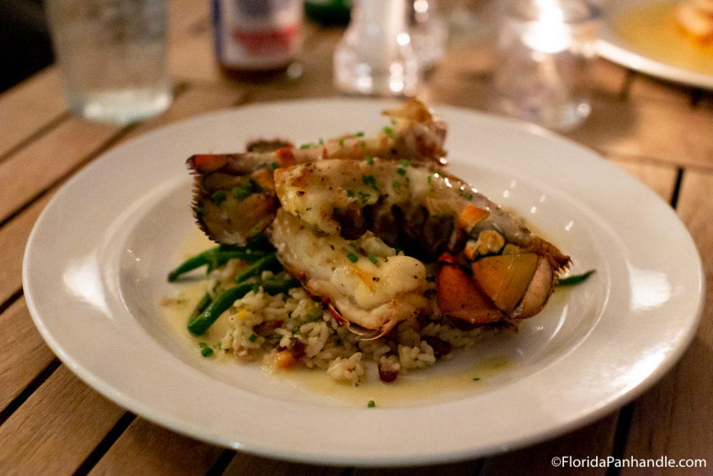 cooked seasoned lobster tail on a bed of wild rice and green beans at The Grand Marlin in Pensacola Beach Florida