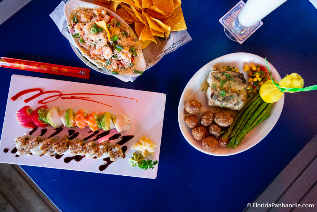 a plate of sushi rolls next to a plate of grilled fish with asparagus at Flounder's Chowder House