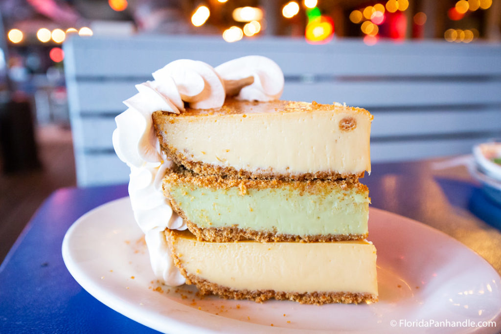 a layered stack of yellow and green key lime pie with whipped cream on the crust