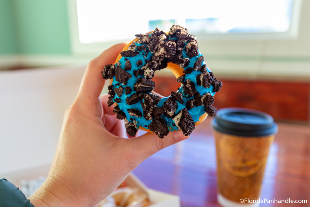 A blue frosted donut with crushed oreo's on top at Although A'More Donuts