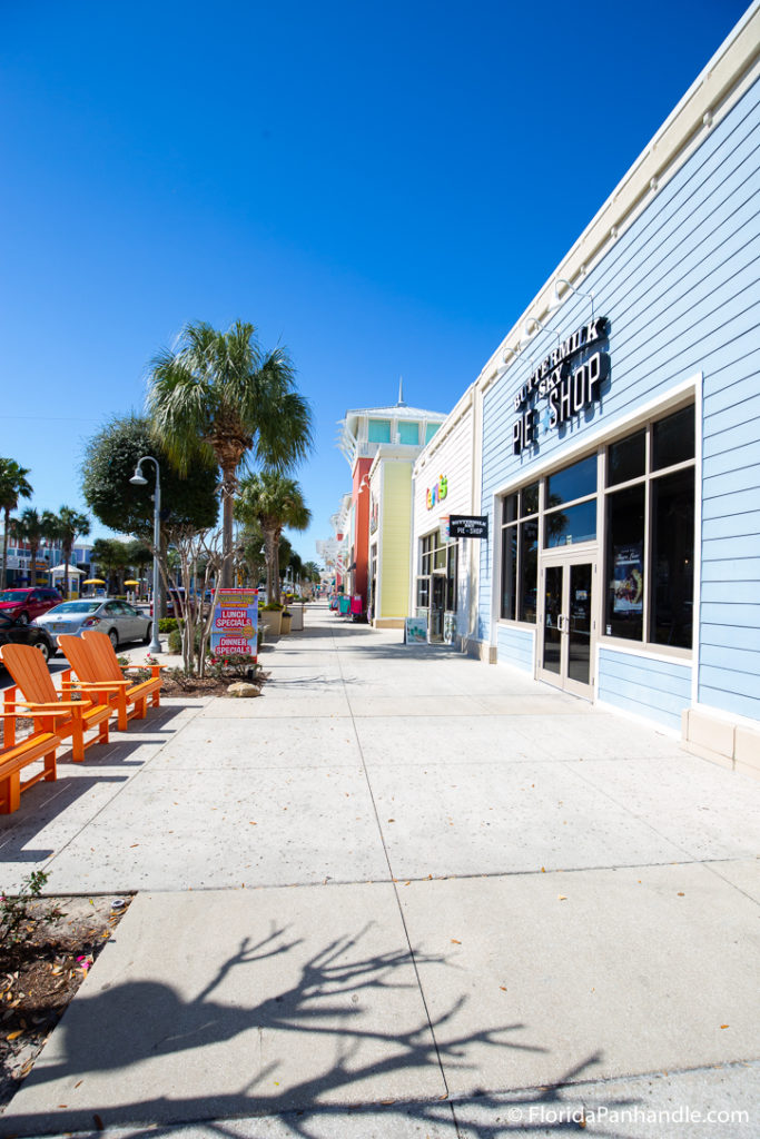 walking down the sidewalk with gift shops and lounge beach chairs at Pier Park