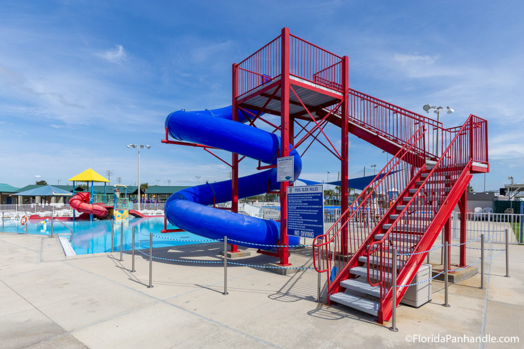 water park with big red stairs connected to royal blue colored tube water slide and red tube water slide in the distance