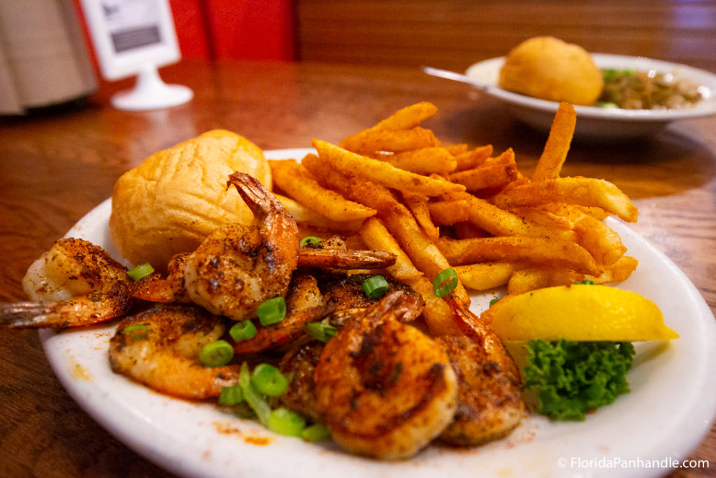 grilled and blackened shrimp with green onion next to sweet potato fries and lemon