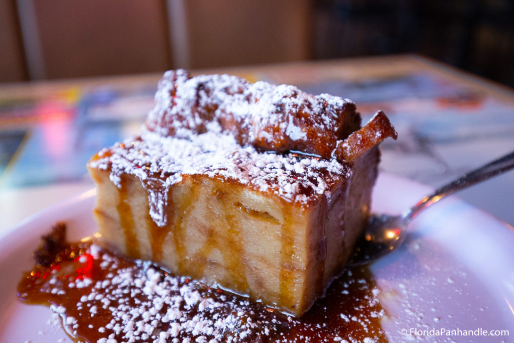 plate of sweet dessert bread with a berry syrup and powdered sugar on top at Dat Cajun Place