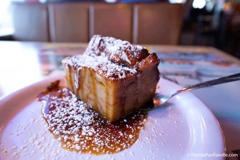 bourbon glaze bread pudding with sprinkled sugar on top of white plate at local restaurant in florida