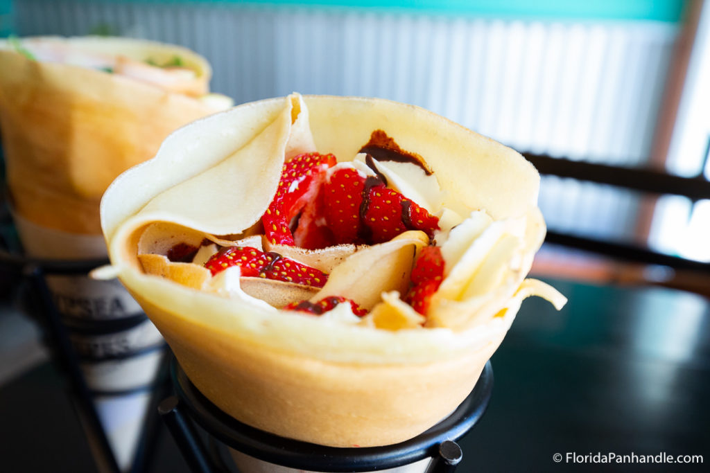 a crepe filed with strawberries, whipped cream and chocolate syrup