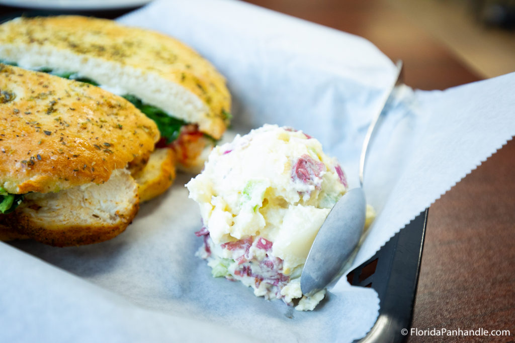 a pesto chicken sandwich with a scoop of potato salad on the side at Liza's Kitchen in Panama City Beach Florida