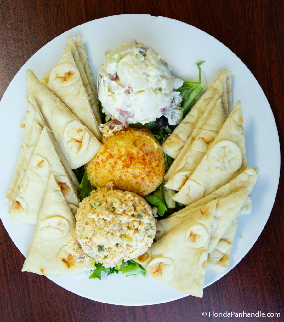 three types of dips with slices of pita on the side