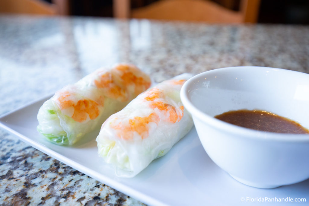 a plate of spring rolls with a side of dipping sauce