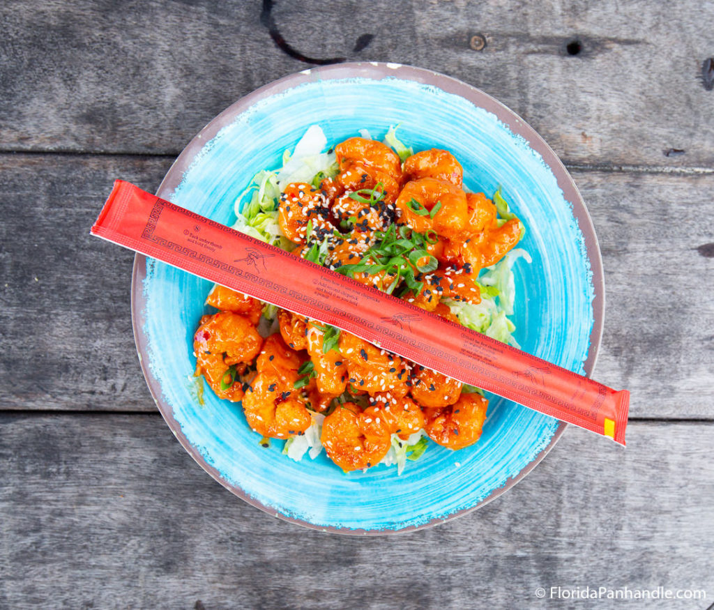 a plate of boom boom shrimp with a pair of unopened chopsticks over top at Sharky's Beachfront Restaurant