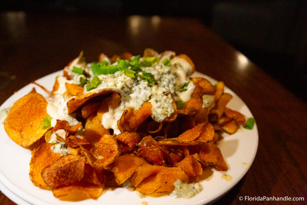 sweet potato chips with cheese and chives on top at oyster bar in pcb