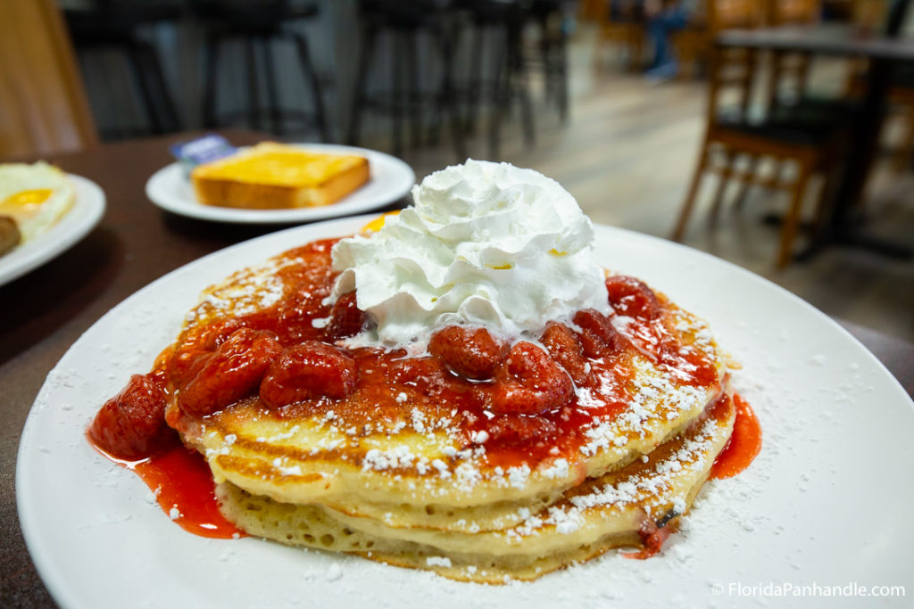 a stack of pancake with strawberry syrup and whipped cream on top