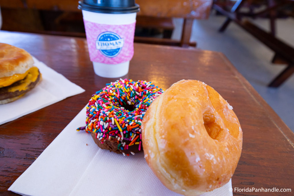 one glazed donut and one chocolate, chocolate frosted with rainbow sprinkles donut with a cup of coffee at Thomas Donut & Snack Shop 