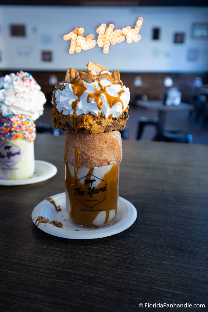 a vanilla caramel milkshake with a thick moist cookie, whipped cream, caramel drizzle and cinnamon toast crunch cereal pieces on top at The Yard Milkshake Bar of Destin