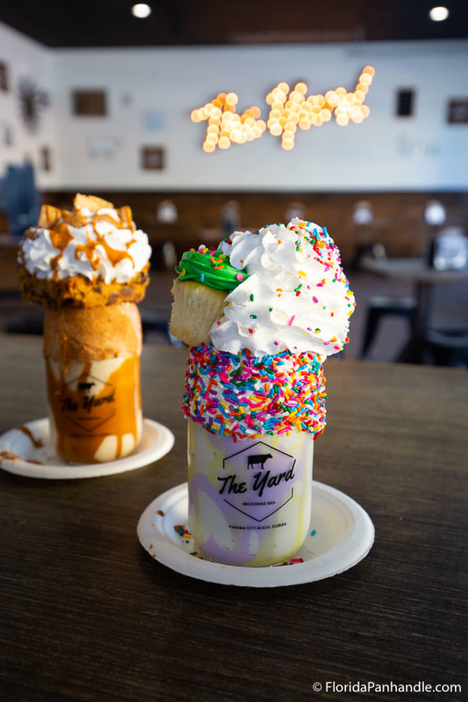 two milkshakes side by side with whipped cream and sprinkles on top