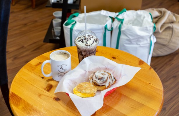 a tray with a cinnamon roll and a breakfast egg biscuit with an iced coffee and a hot coffee on the side at Deja Brew Coffee Shop in Panama City Beach, Florida