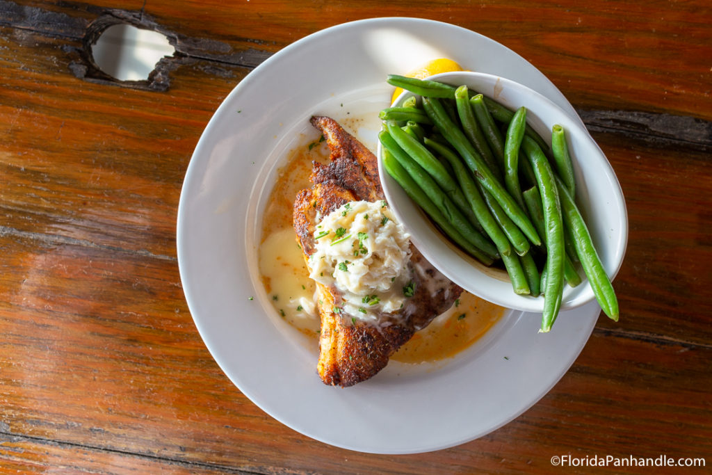 grilled fish with butter and chives on top with a side of green beans at Runway Island in Panama City Beach