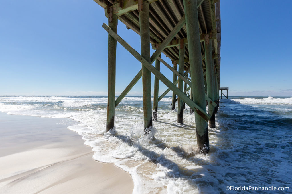 a view of underneath a pier from the beach