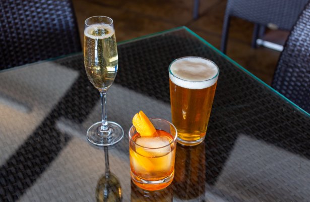 a cocktail, champaign and a beer on a glass top outdoor wicker table at the Craft Bar