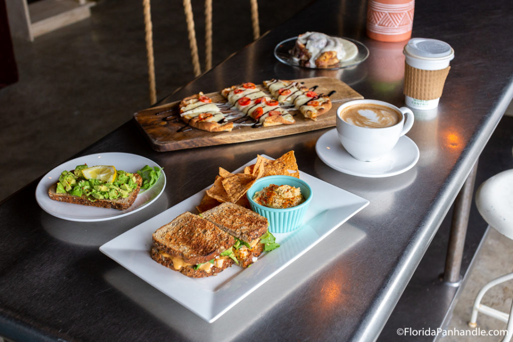 plate of avocado toast, sandwich, and cheese pizza with tomatoes and vinaigrette drizzle with a cup of coffee at The Pour 