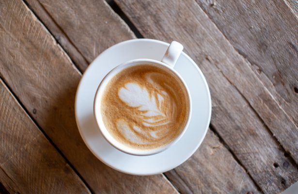 a cup of coffee with milk foam on top in the shape of a leaf at The Pour in Panama City Beach, Florida