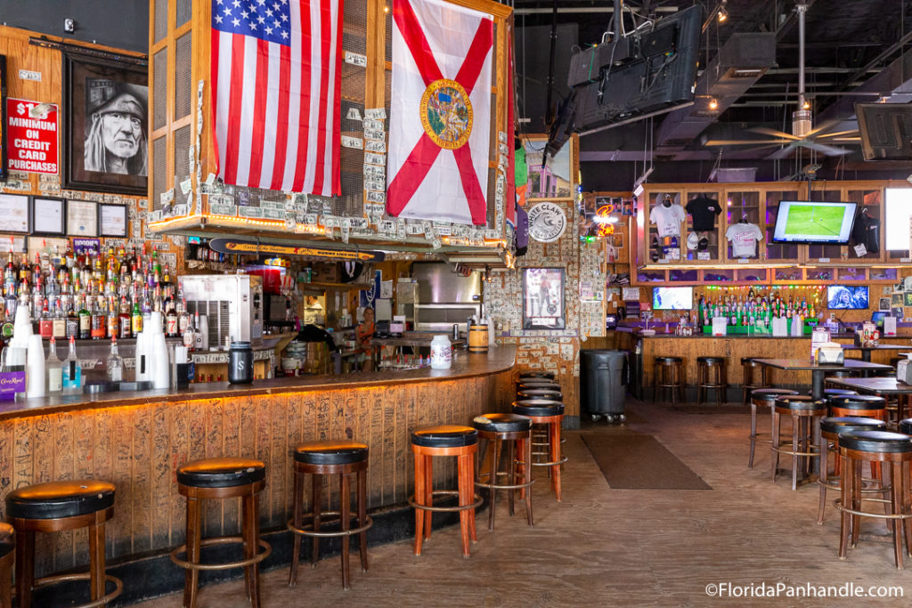 a full wooden bar with money stapled to the walls and a hanging American flag at Tootsie's Orchid Lounge