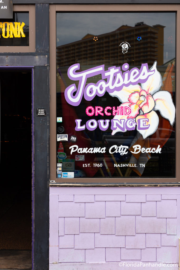 a sign of Tootsies Orchid Lounge in the window of their building in Panama City Beach Florida