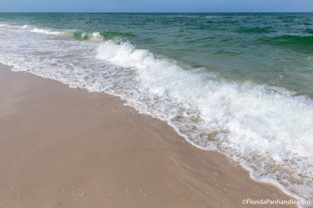 waves washing up on the shoreline on a sunny day with blue skies