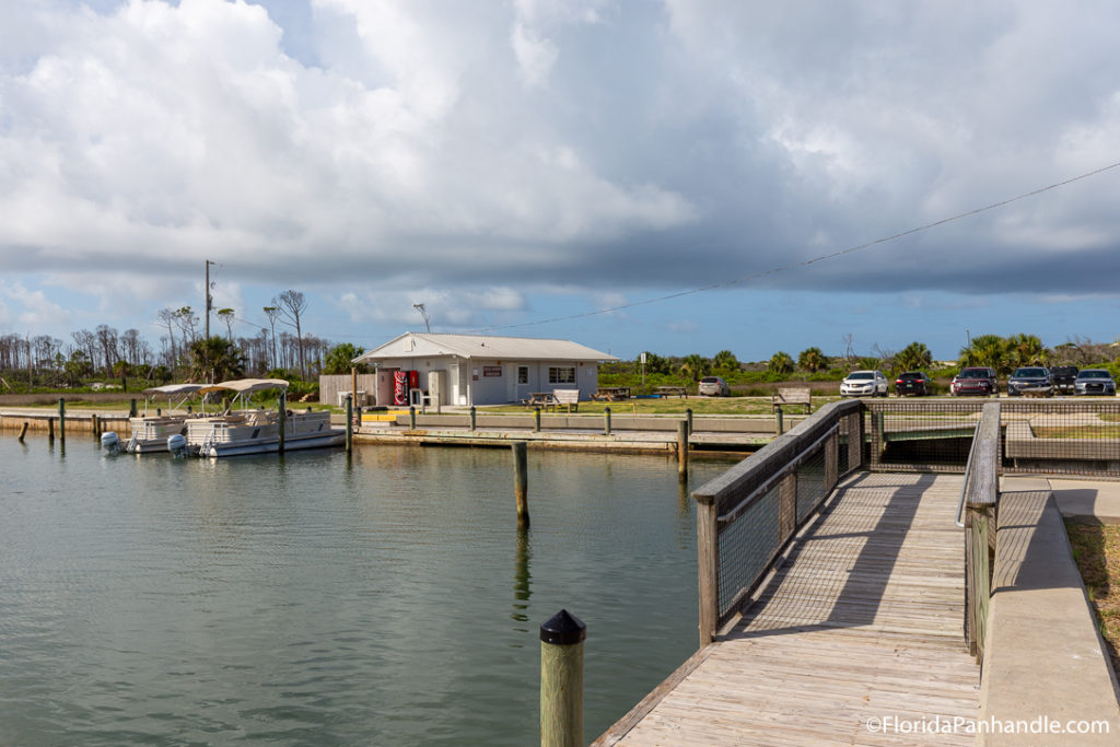 fishing dock on the water and two fishing boats in the distance with big clouds in the sky