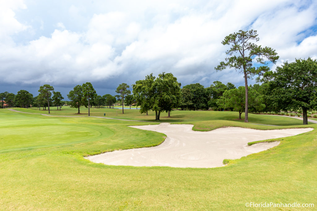 a large area of green grass with a spot of sand bunker