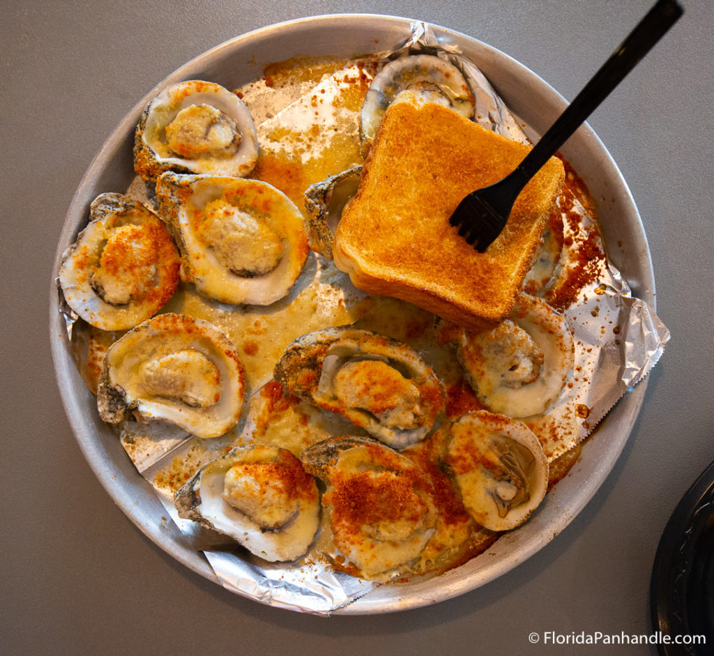 plate of open cooked clams with chili powder on top and a piece of toast on top with a fork in it