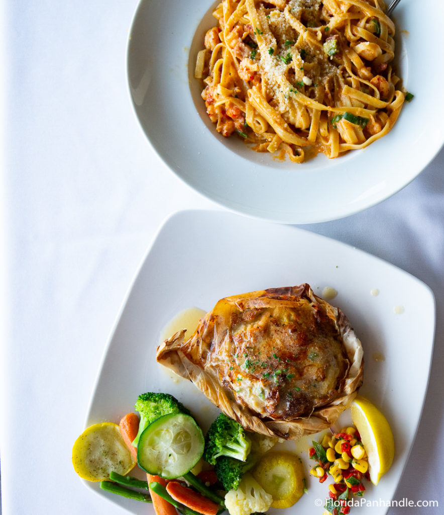 a baked chicken thigh with a side of veggies and  plate of pasta with parmesan cheese on top