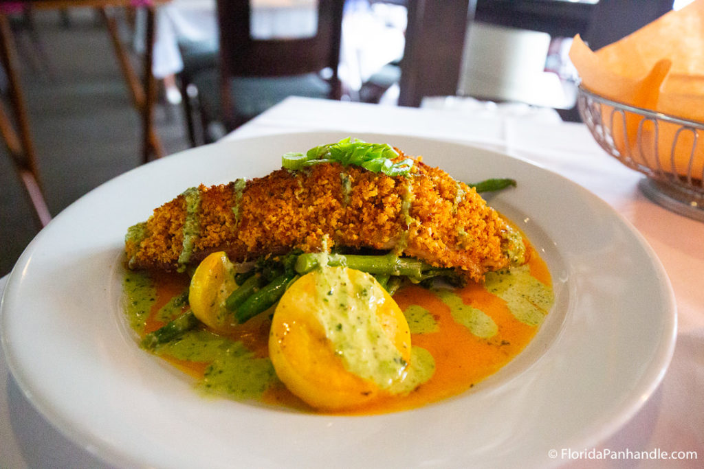 plate of fried fish on top of green beans and squash with green cilantro sauce drizzled on top at Marina Cafe
