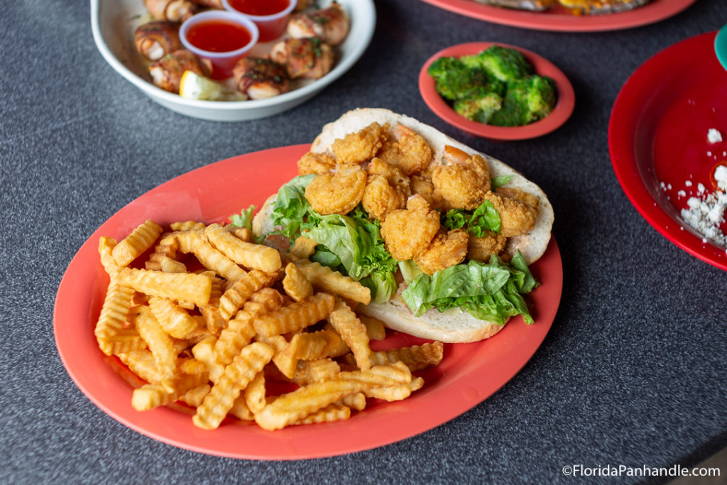 a shrimp and lettuce sandwich with a side of fries at The Sandbar in Pensacola, Florida