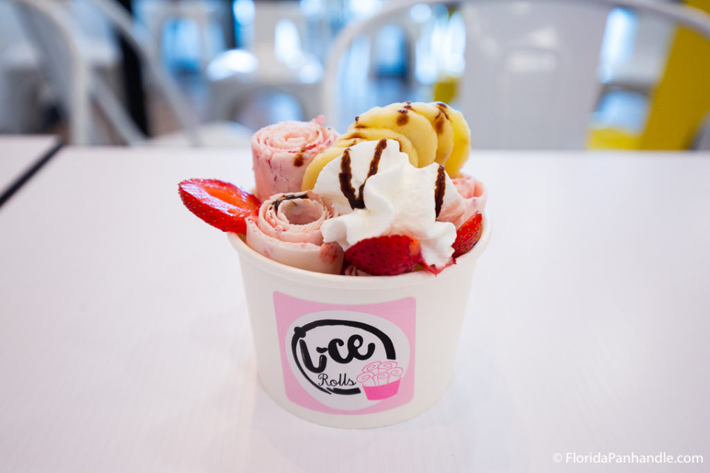 a cup filled with rolled ice cream topped with whipped cream, strawberries and bananas 