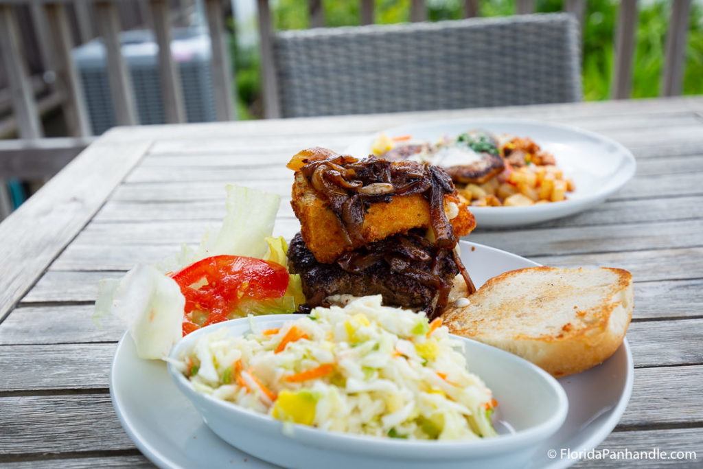 grilled onions on top of fried ring on top of burger next to bun and salad at Stinky's fish camp