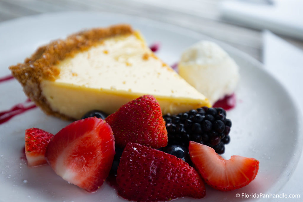 a slice of pie served with sliced fruit and a small scoop of ice cream