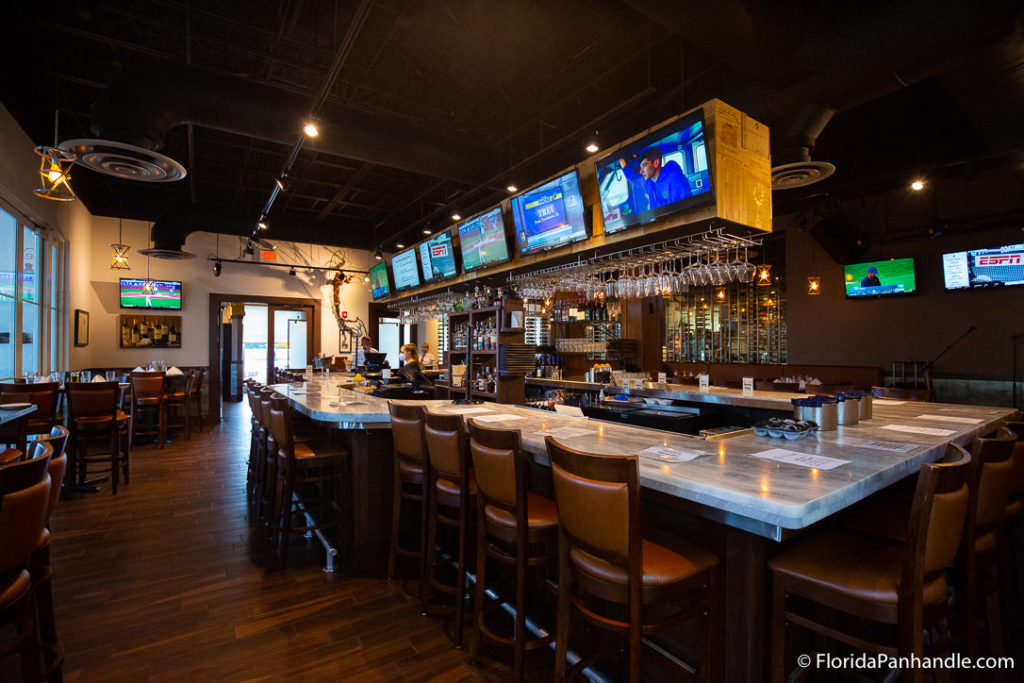 interior of cuvee 30a's bar top with tvs overhead and wine glasses up top