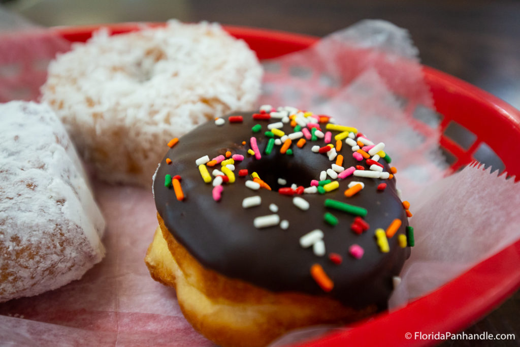 donut shops in destin, chocolate frosted donut with rainbow sprinkles, Donut Hole Bakery and Cafe