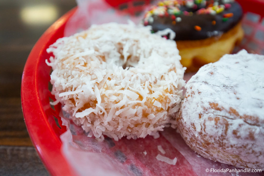 a coconut smothered donut next to a powdered donut at Donut Hole 