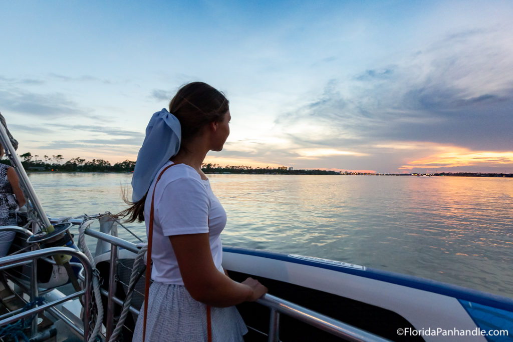 a woman on a boat looking out into the ocean during the sunset