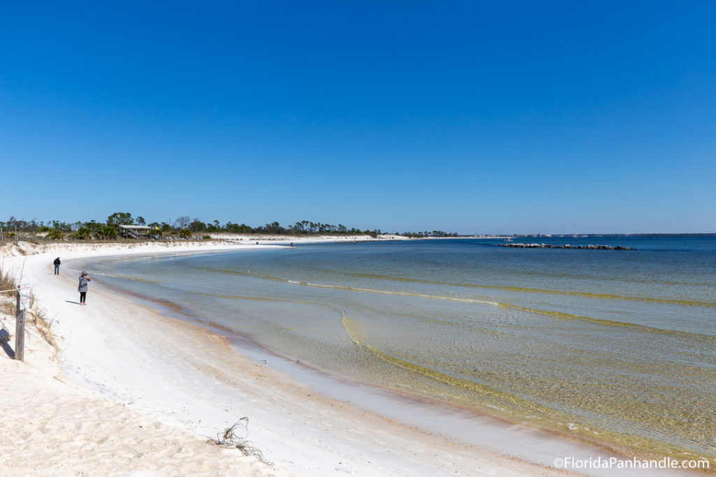 a couple people on the beach while one photographs the views at Jetty Beach in Destin, Florida