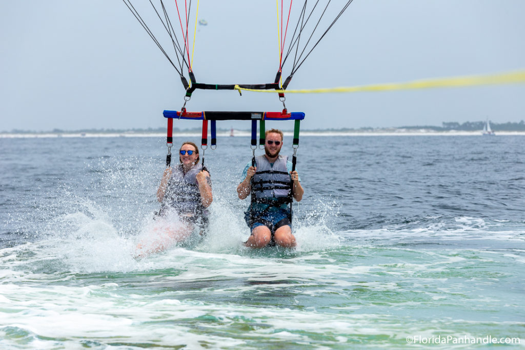a man and women sitting in parasail seats scraping the water